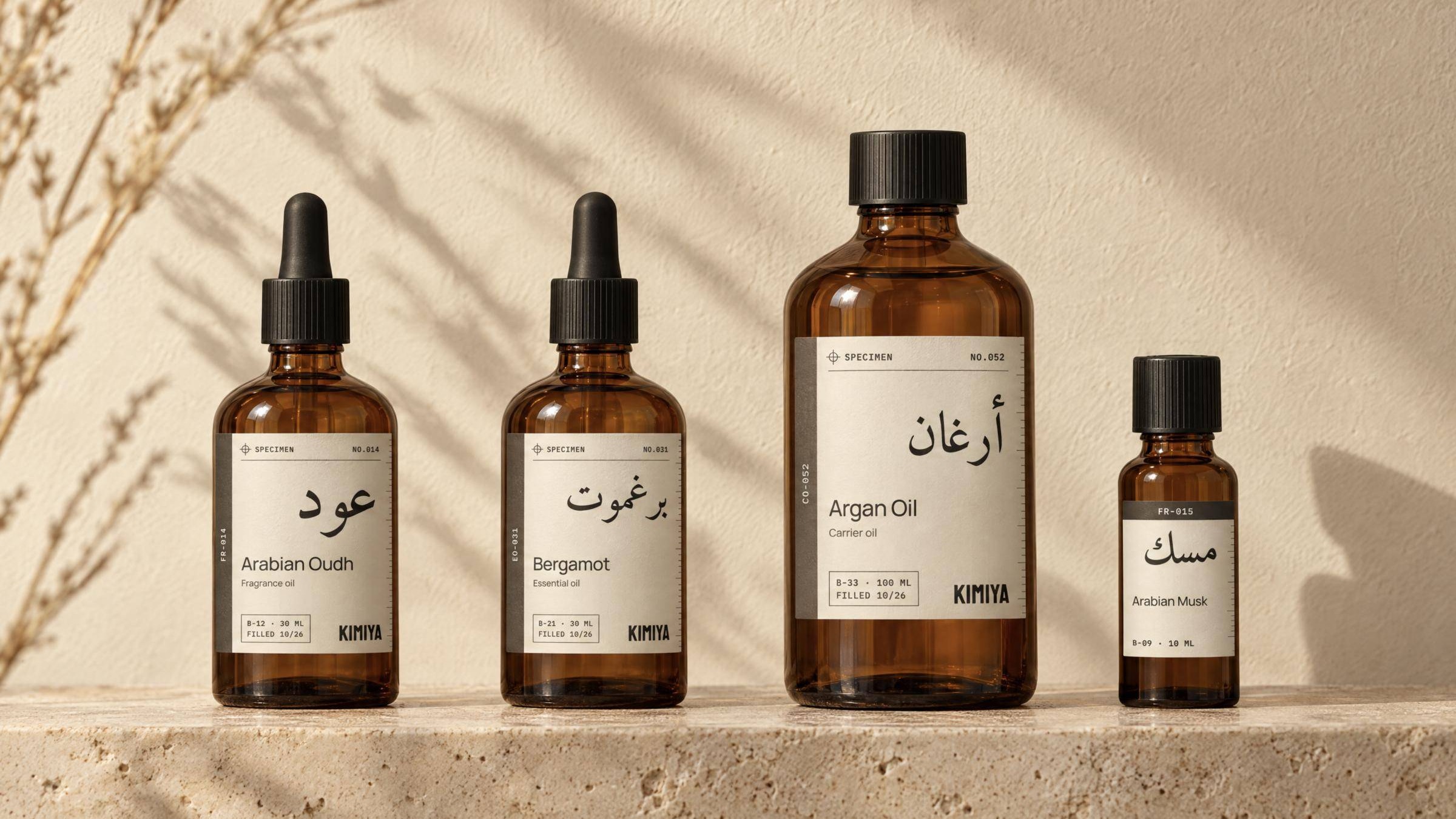 Four amber KIMIYA bottles with specimen labels on a travertine ledge in warm afternoon light