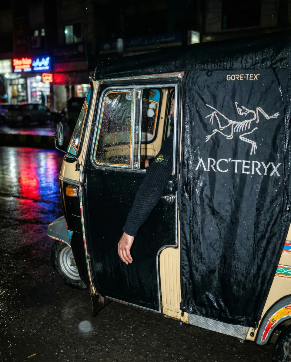 AI-generated image: Technical outerwear graphics on a rain-soaked rickshaw canopy.
